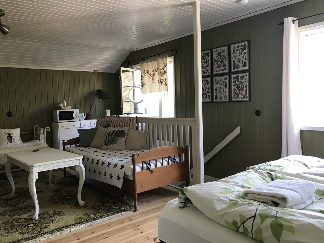 A green-panelled archipelago guest room with botanical prints and two neatly made beds